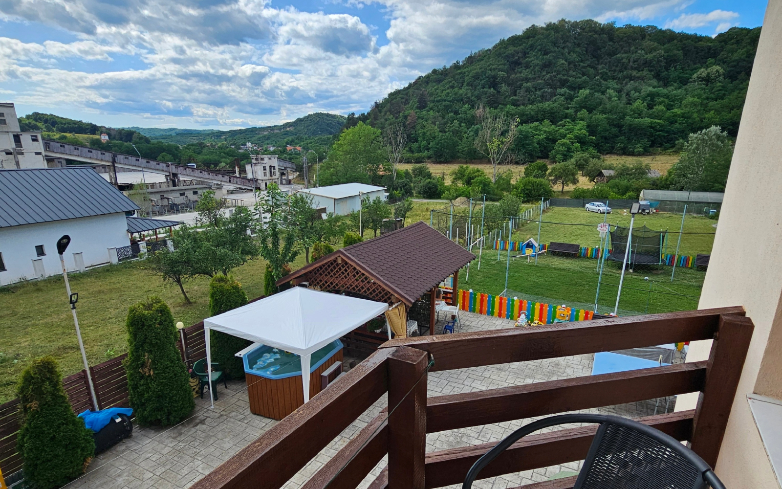Vedere panoramică spre Salina Ocnele Mari din curtea cu ciubăr și loc de joacă pentru copii a Pensiunii Esențial.